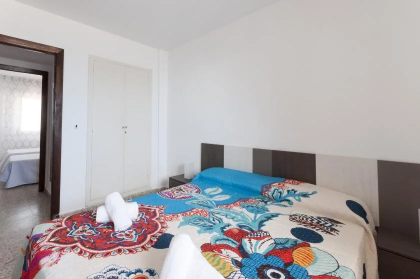 A bedroom with a bed covered in a colorful patterned bedspread.