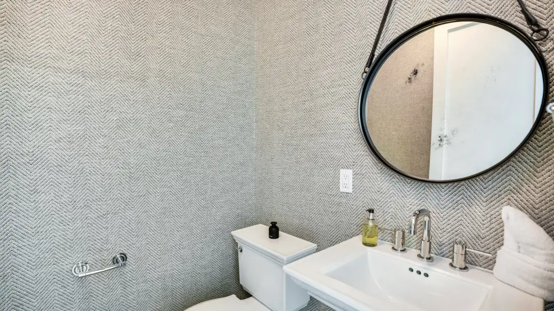 Un lavabo de baño con espejo redondo y un inodoro.