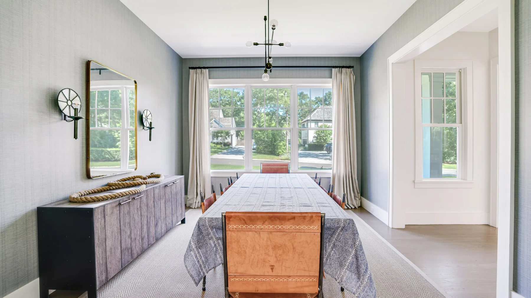 Un comedor luminoso con una mesa larga junto a grandes ventanas.