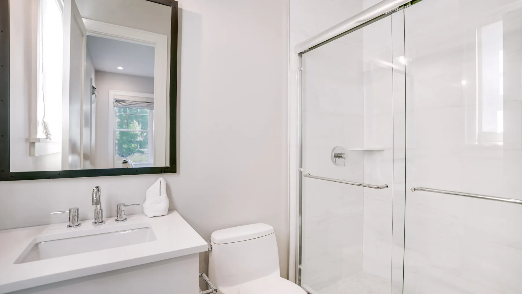 Un baño luminoso con lavabo, inodoro y ducha de vidrio.