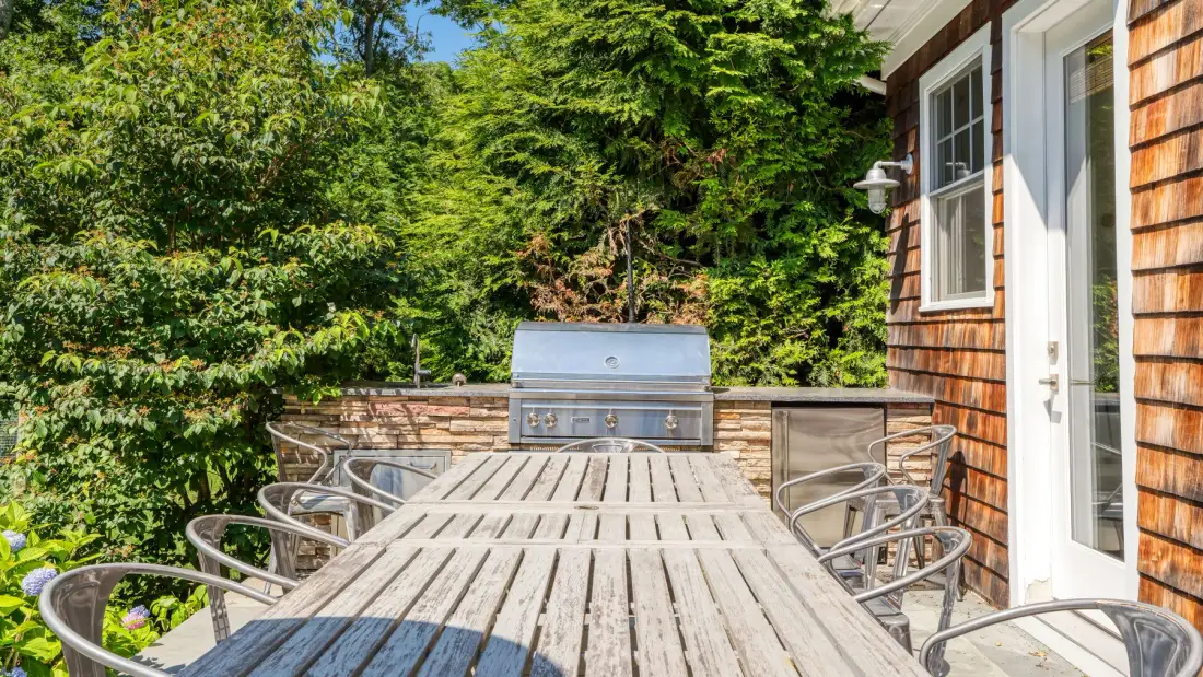 Una terraza exterior con una mesa larga de madera y asientos alrededor.