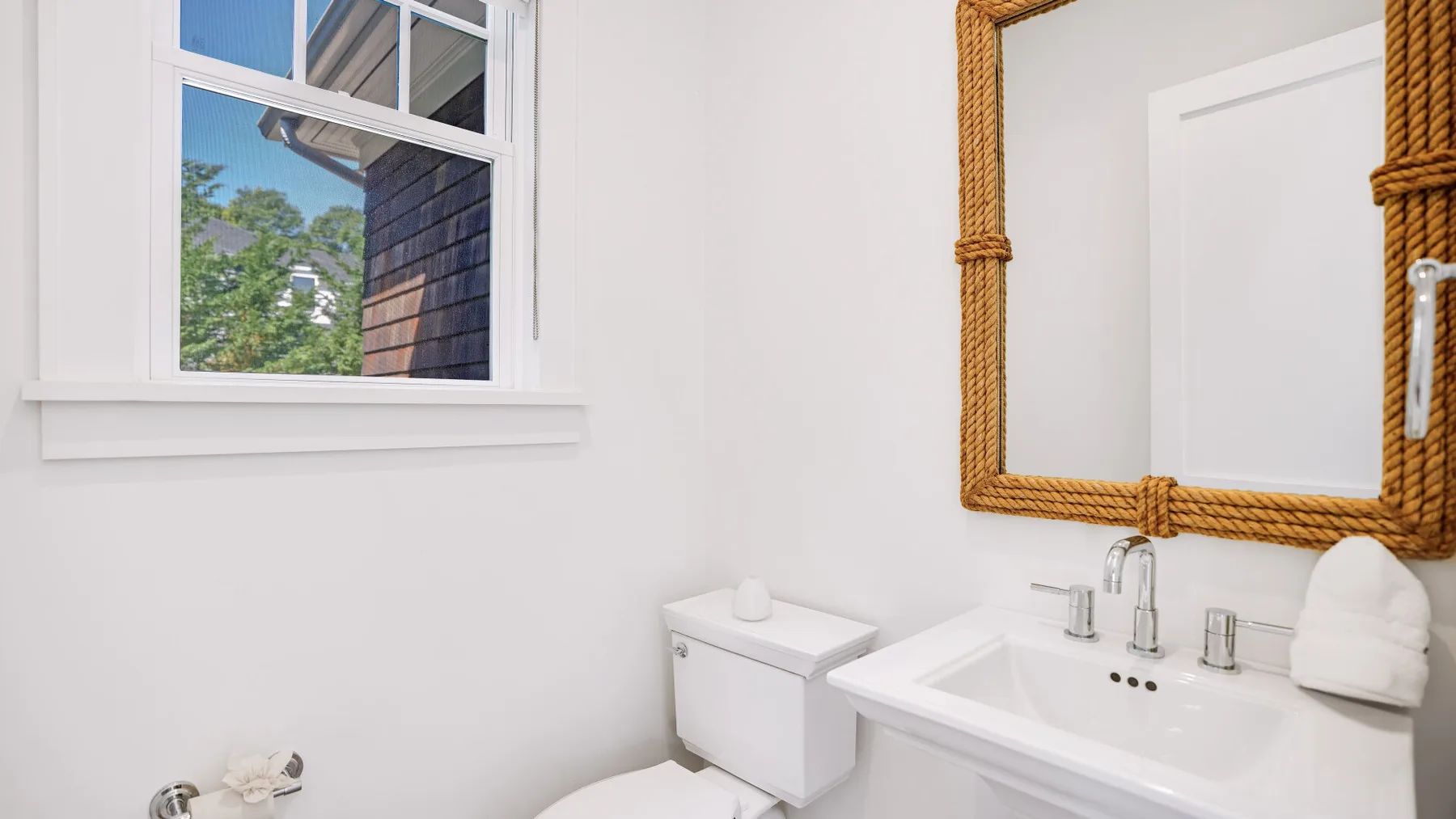 Un baño luminoso con lavabo, espejo y una ventana con vista a la vegetación.