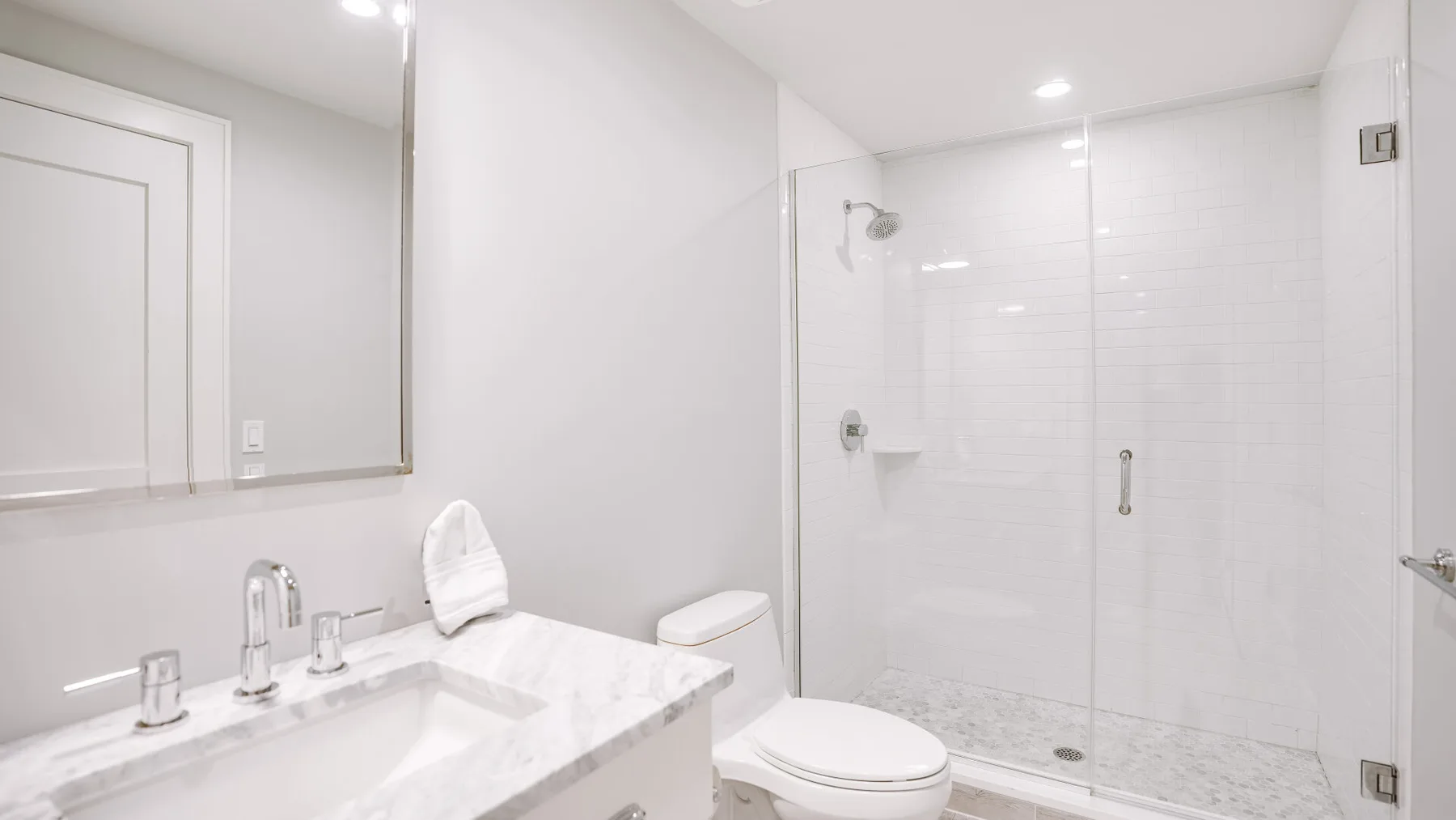 Un baño luminoso con lavabo, espejo, inodoro y ducha de vidrio.
