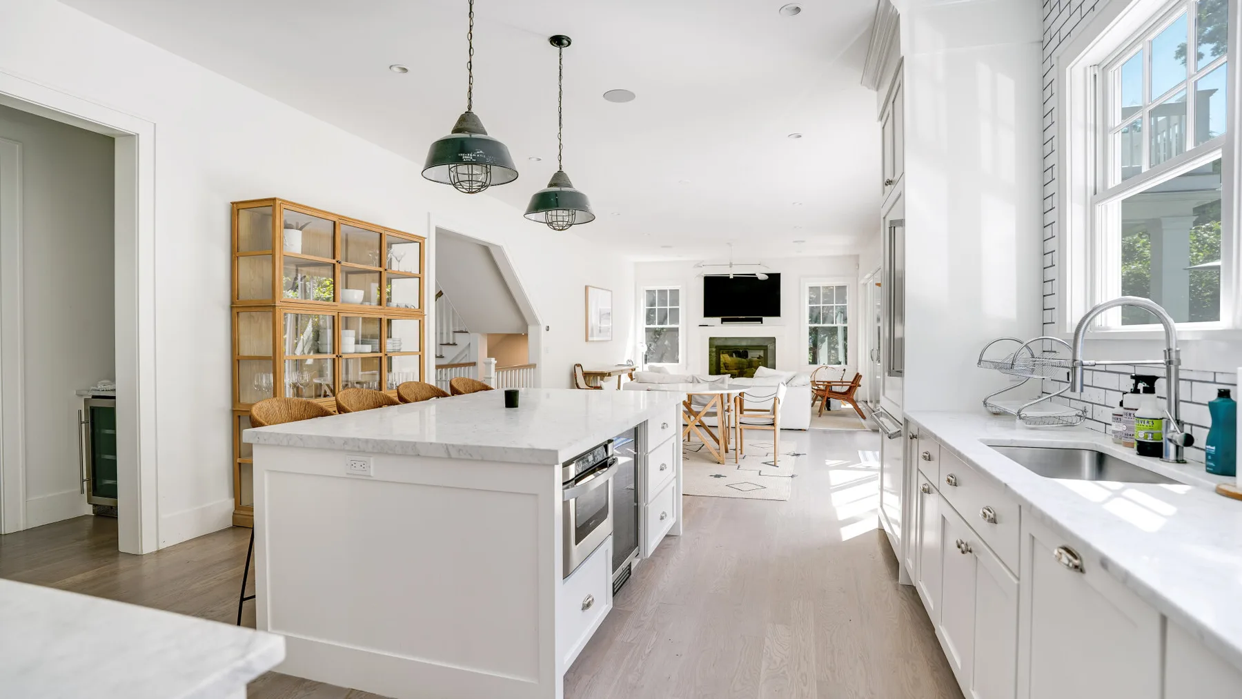 Una cocina luminosa con una isla central, gabinetes blancos y ventanas grandes.