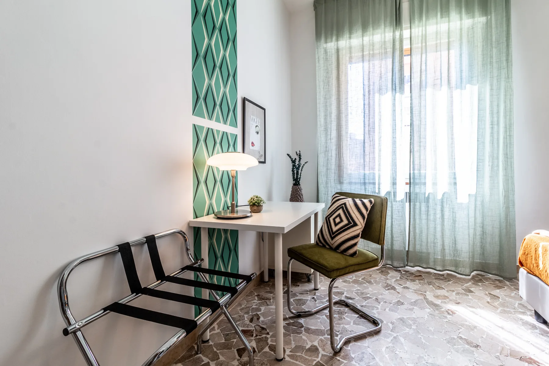 Una zona de estar con una mesa pequeña, sillas y cortinas translúcidas en la ventana.