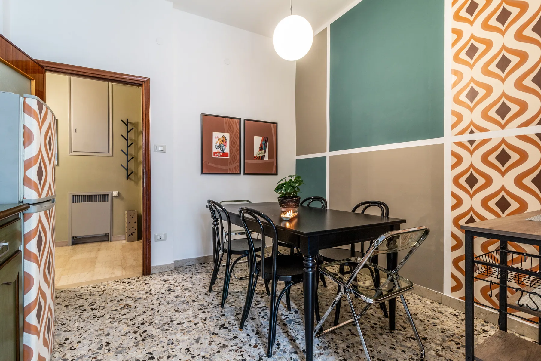 Comedor con una mesa negra, sillas y paredes con patrones geométricos.