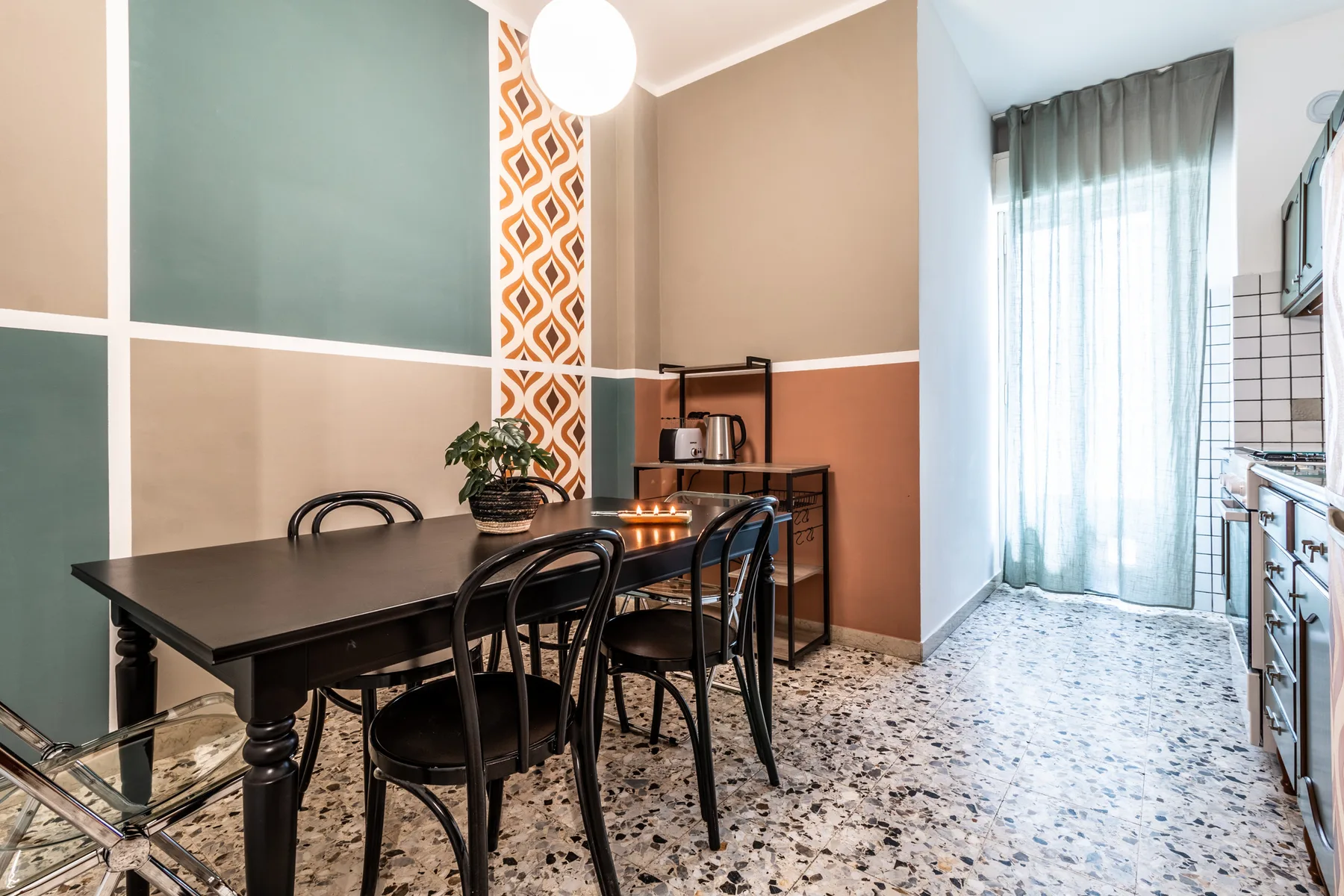Un comedor con una mesa oscura y sillas junto a una cocina pequeña.