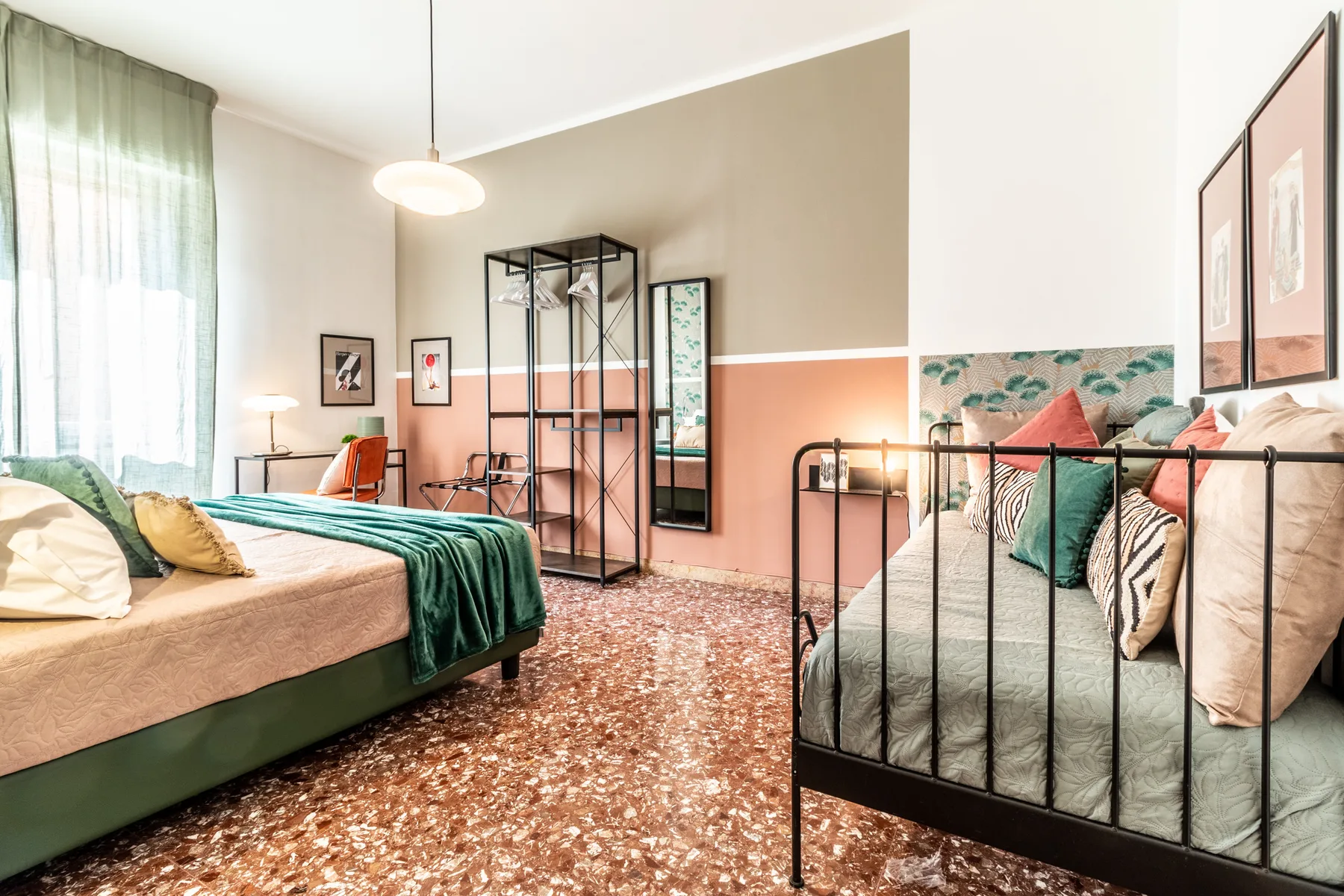 Un dormitorio con dos camas, estructuras metálicas negras y un suelo estampado.