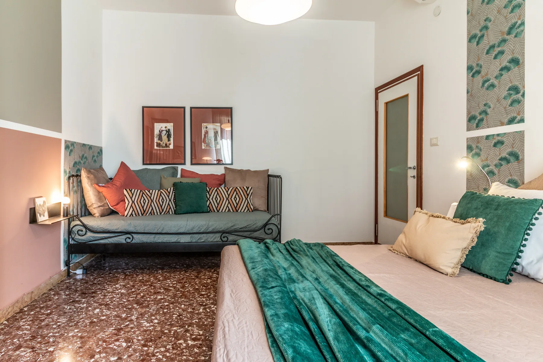 Un dormitorio con una cama cubierta de tela verde azulado y una zona de estar.