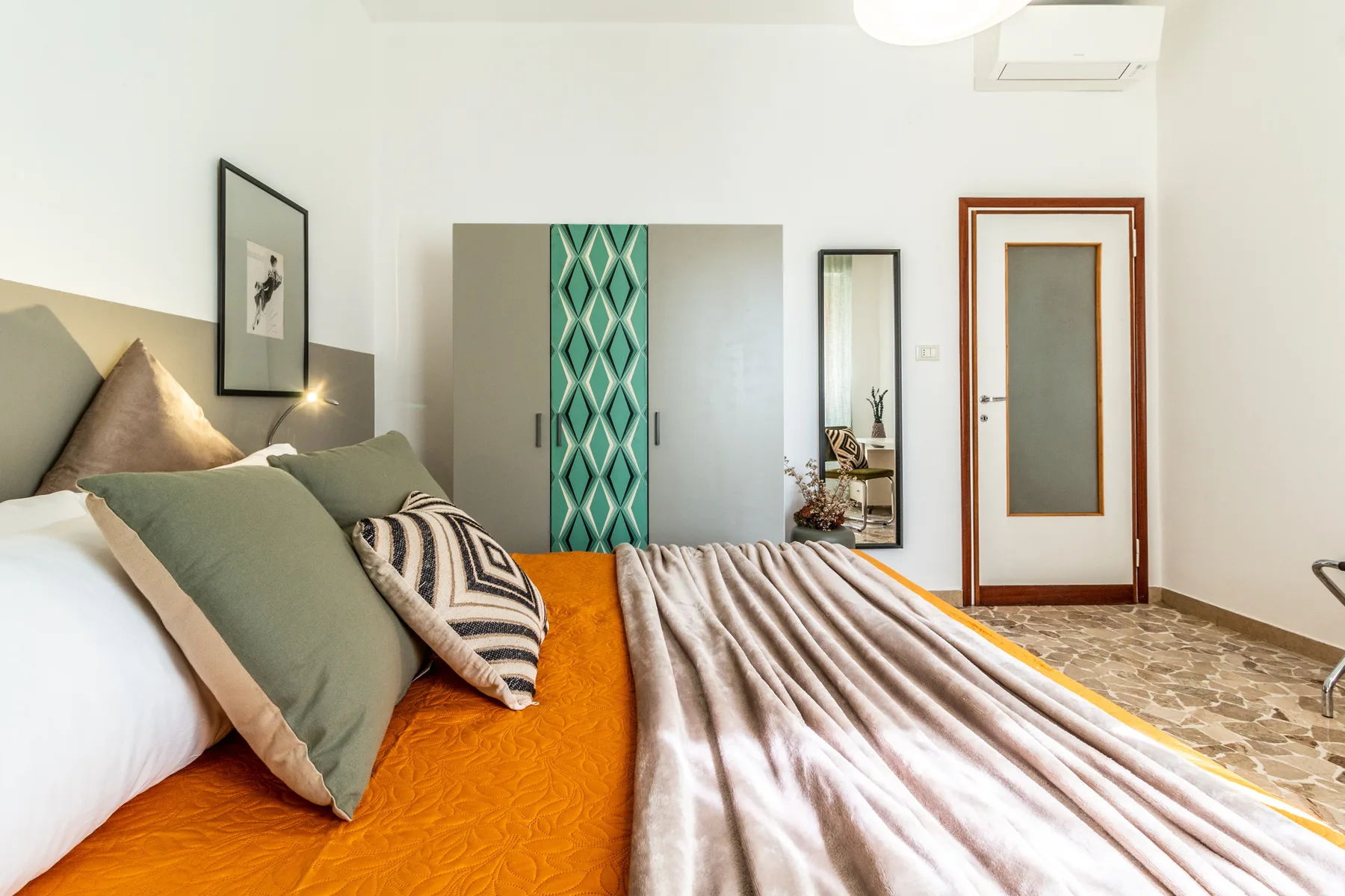 Un dormitorio con una cama, cortinas estampadas y una puerta.