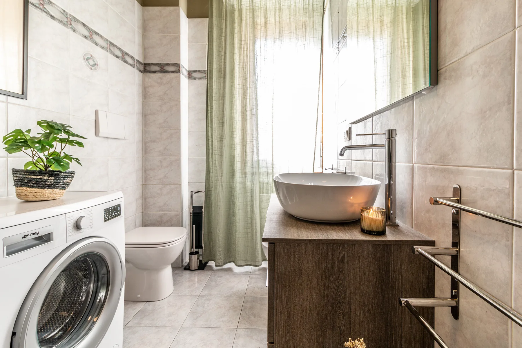 Un baño luminoso con lavabo sobre encimera, inodoro y lavadora.