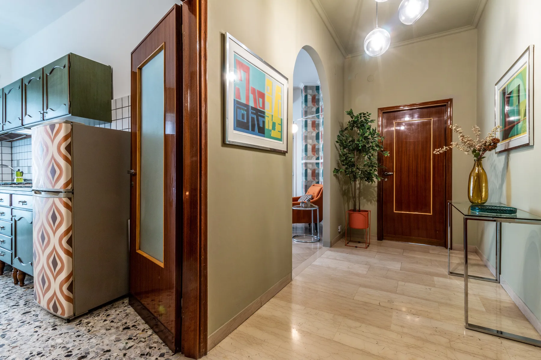 Un pasillo con una puerta de madera, cuadros enmarcados y una consola.