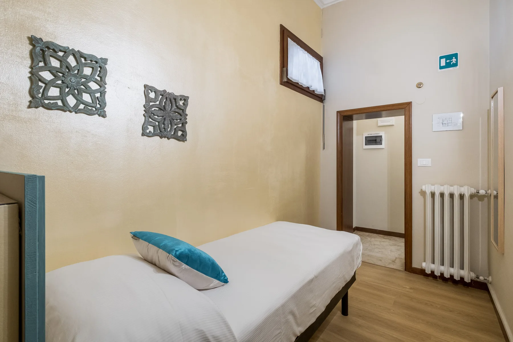Un dormitorio con una cama y una almohada turquesa junto a una puerta.
