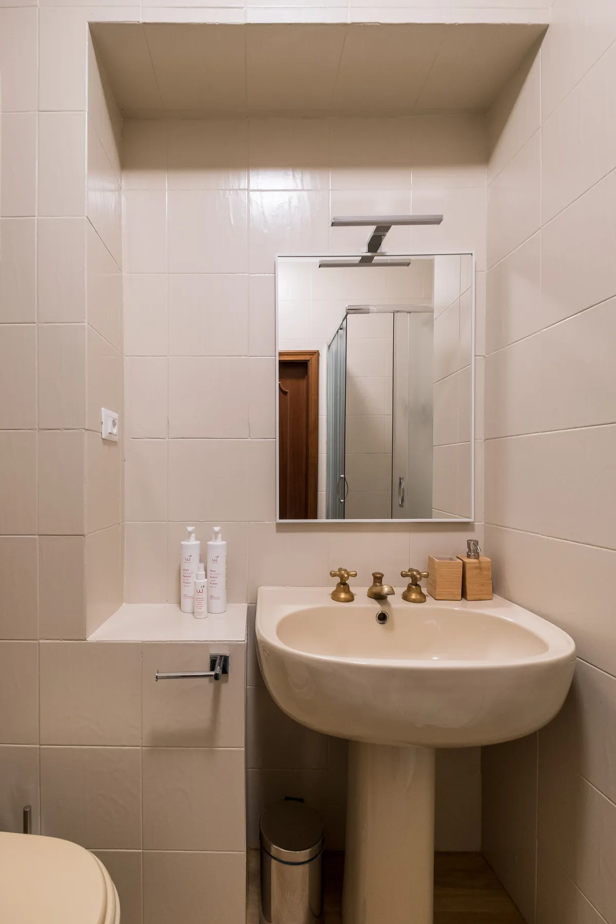 Un baño con azulejos, lavabo, espejo e inodoro.