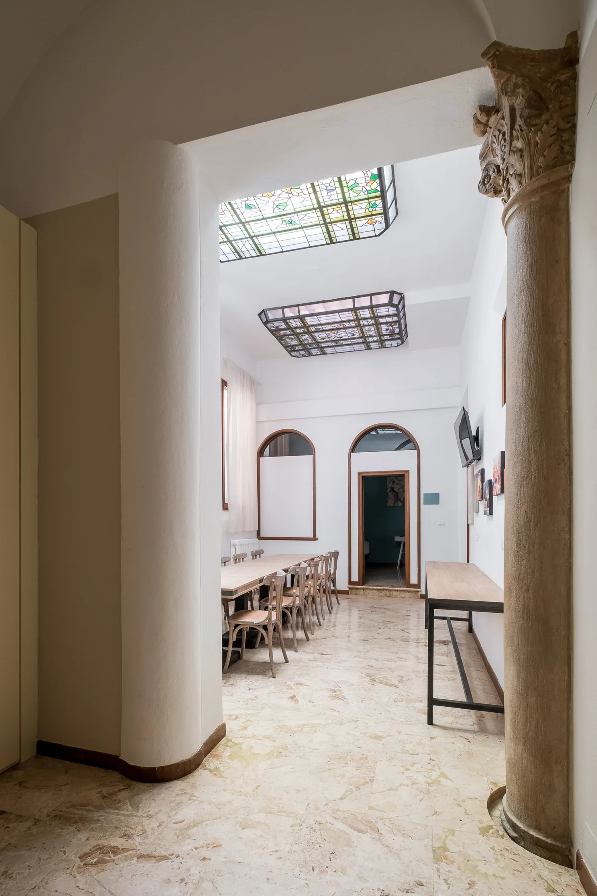 Un comedor luminoso con una mesa larga bajo luces decorativas en el techo.