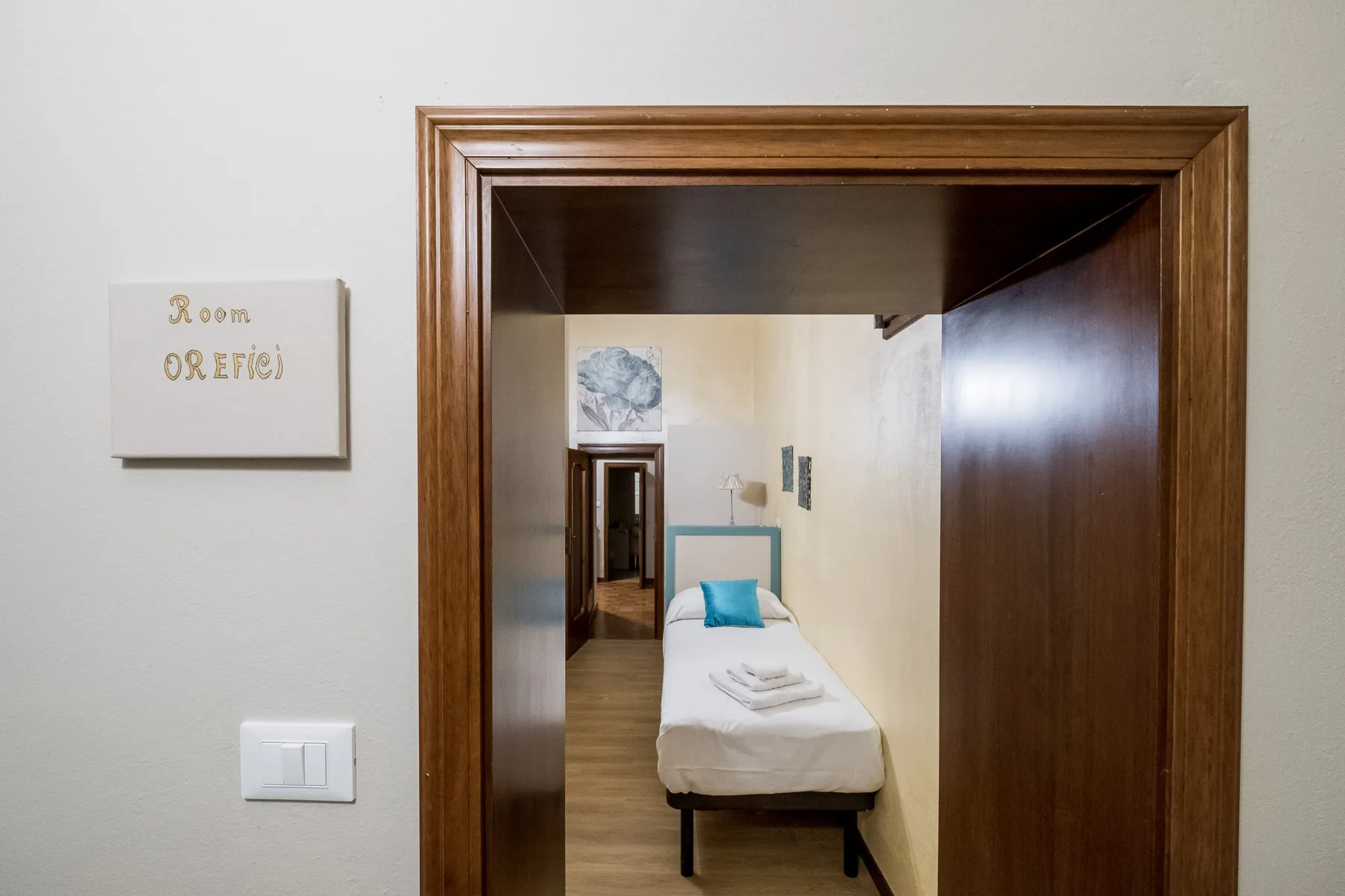 Un dormitorio estrecho con una cama individual y una almohada turquesa.