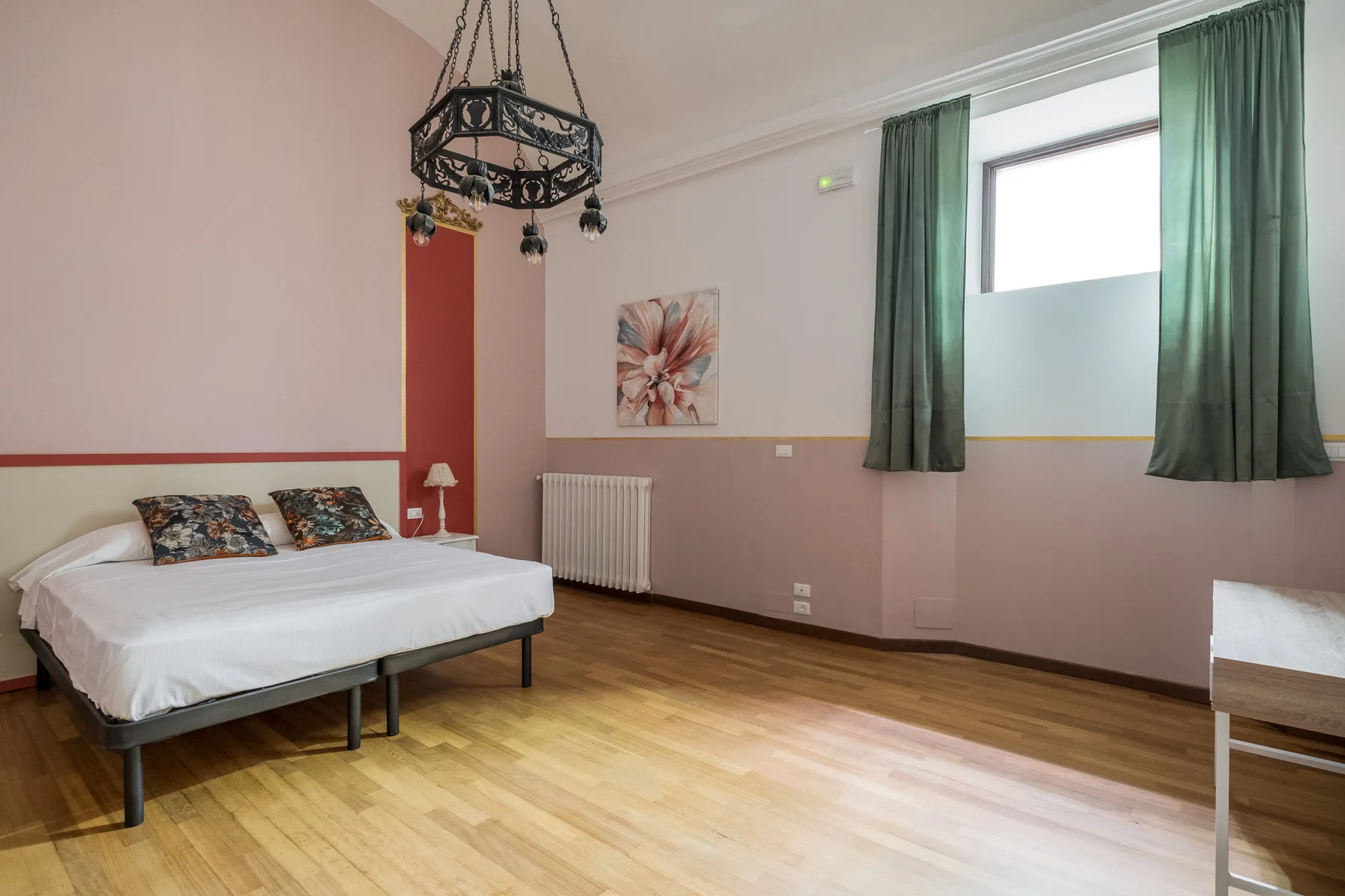 Un dormitorio con una cama doble, cortinas verdes y suelo de madera.