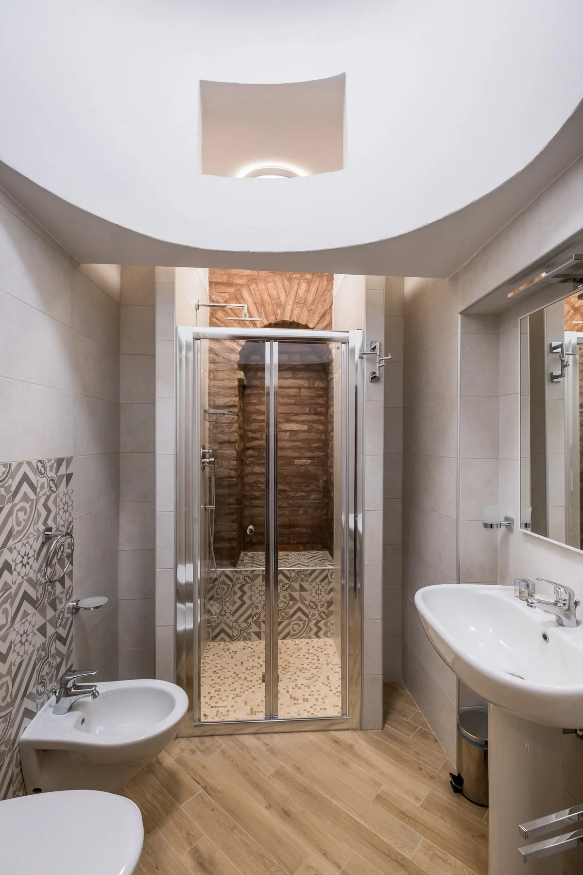 Un baño con ducha de vidrio, lavabo y detalles decorativos en la pared.