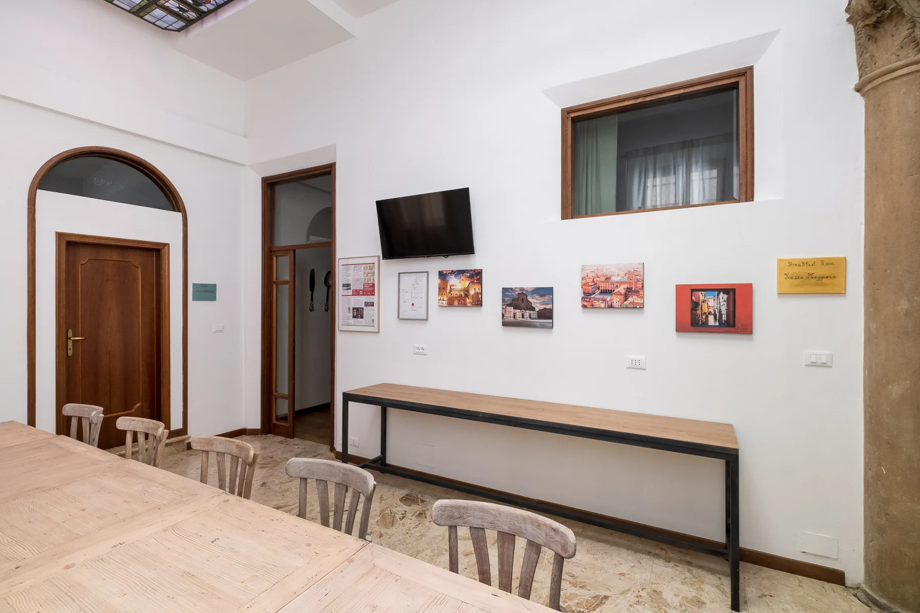 Un comedor con una mesa larga y sillas bajo cuadros en la pared.