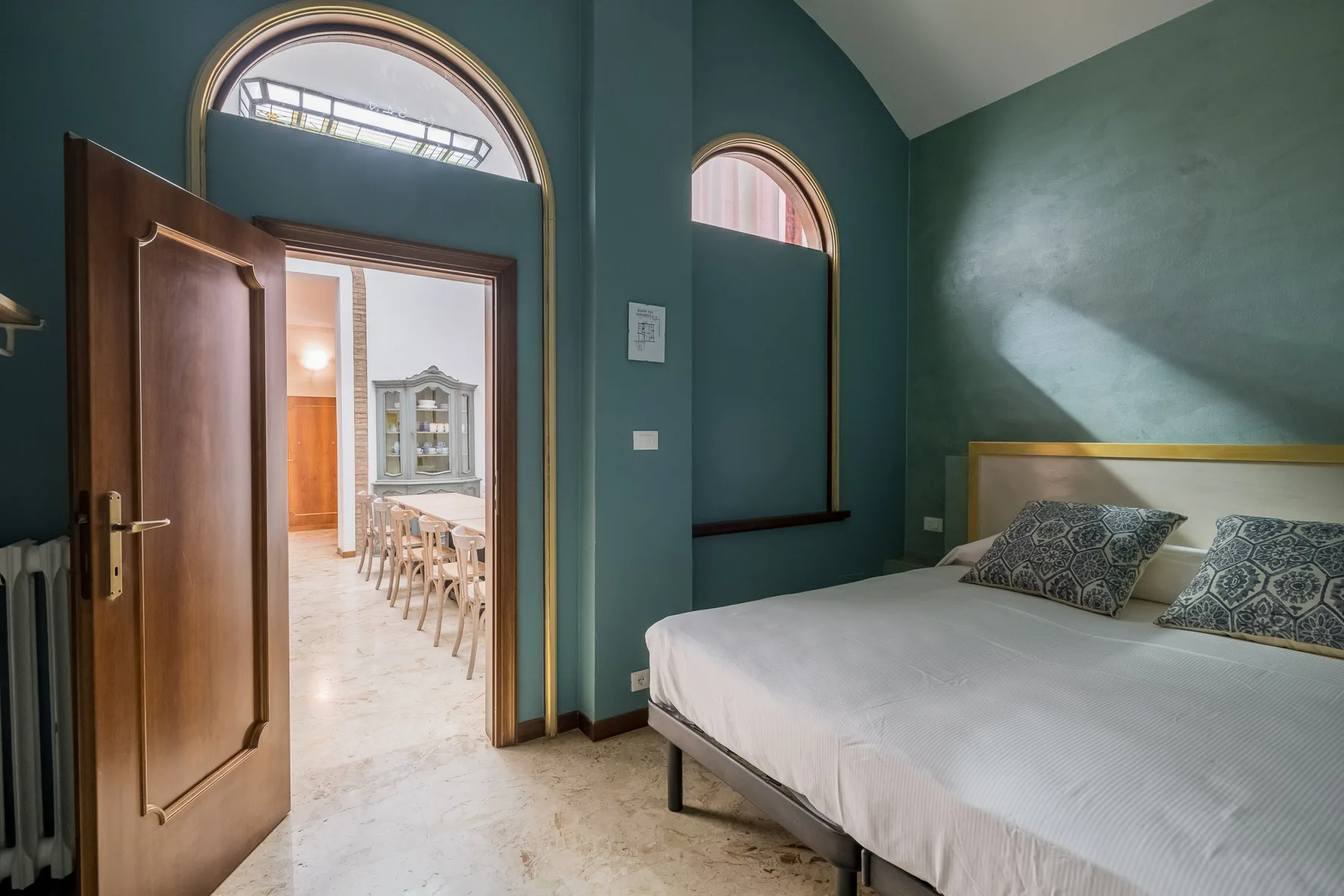 Un dormitorio con una cama junto a una puerta de madera abierta.