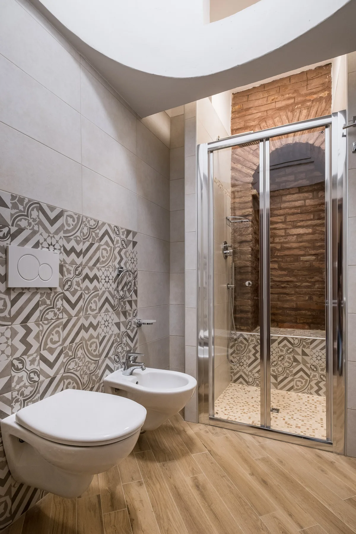 Un baño alicatado con inodoro, lavabo y una ducha con mampara de vidrio.