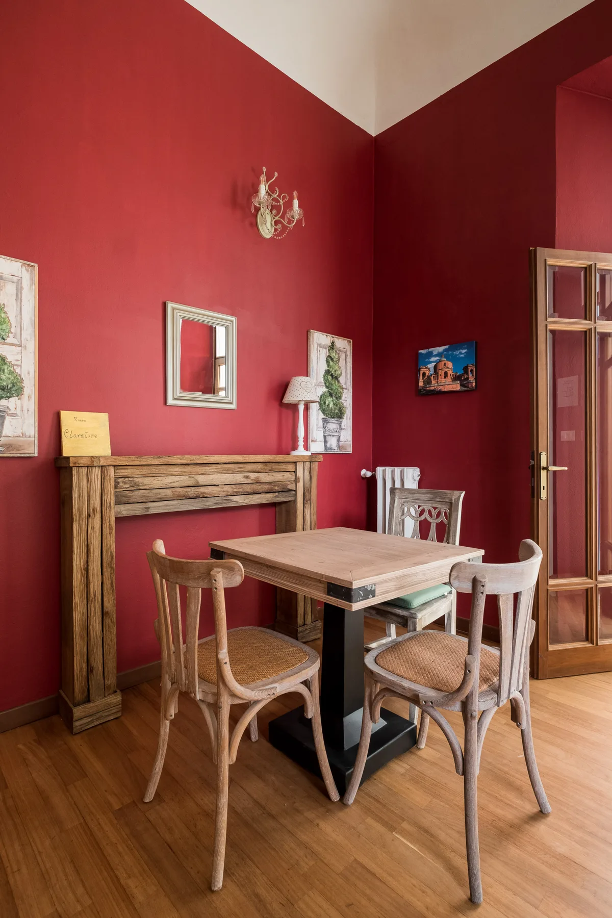Comedor con una mesa de madera y sillas junto a paredes rojas.