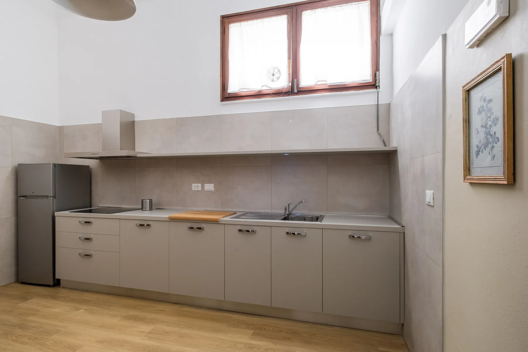 Una cocina luminosa con una encimera larga, armarios y una ventana.