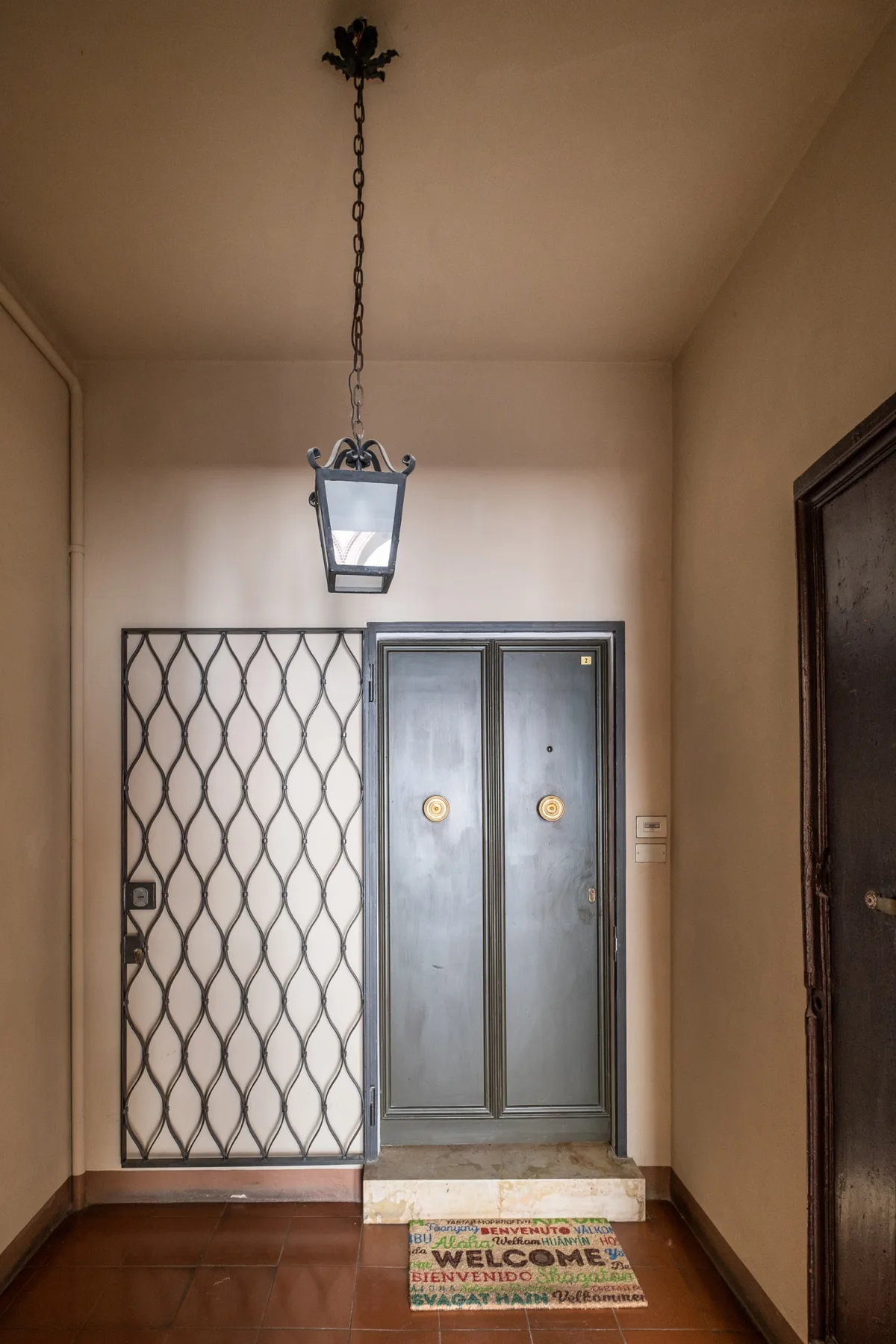 Un recibidor interior con puertas dobles, una pantalla metálica decorativa y un farol colgante.