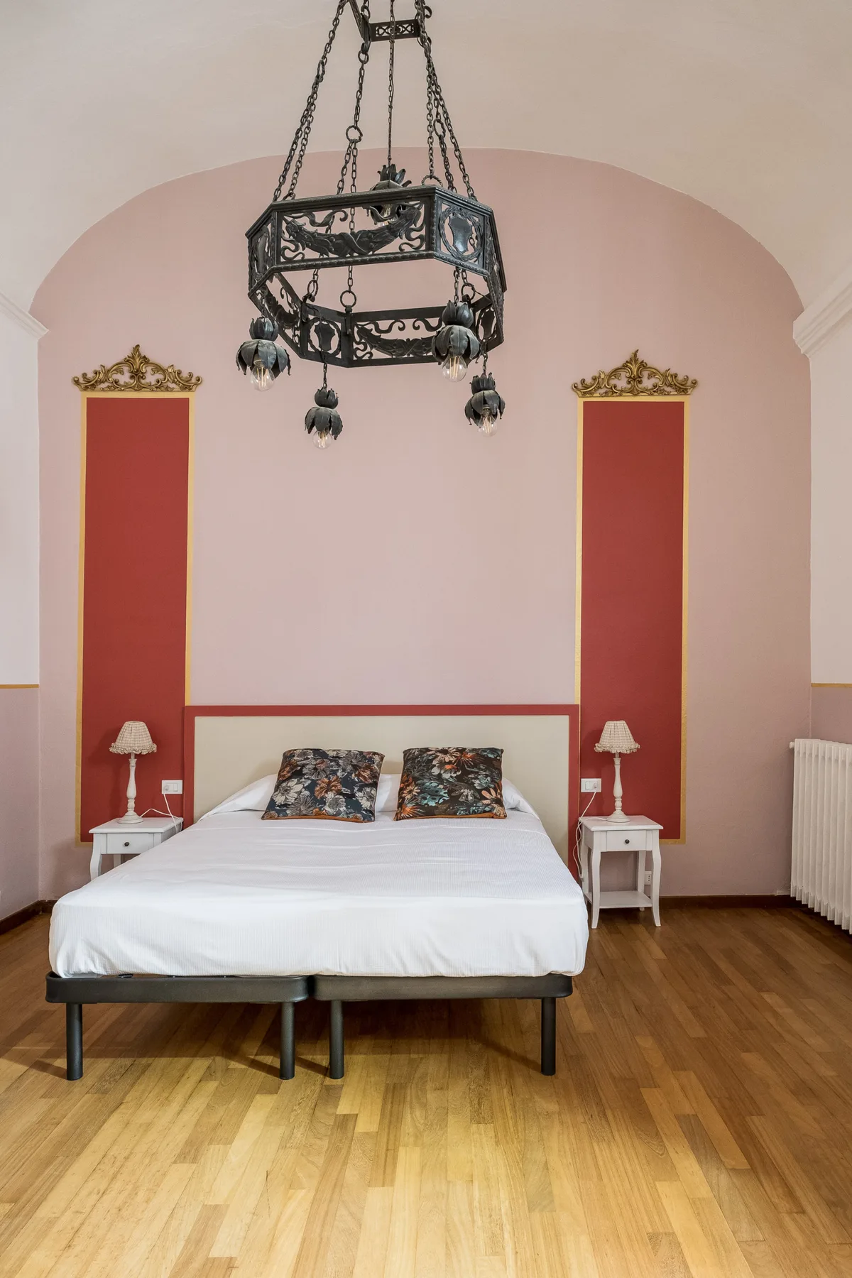 Un dormitorio con una cama bien tendida bajo una lámpara colgante decorativa.