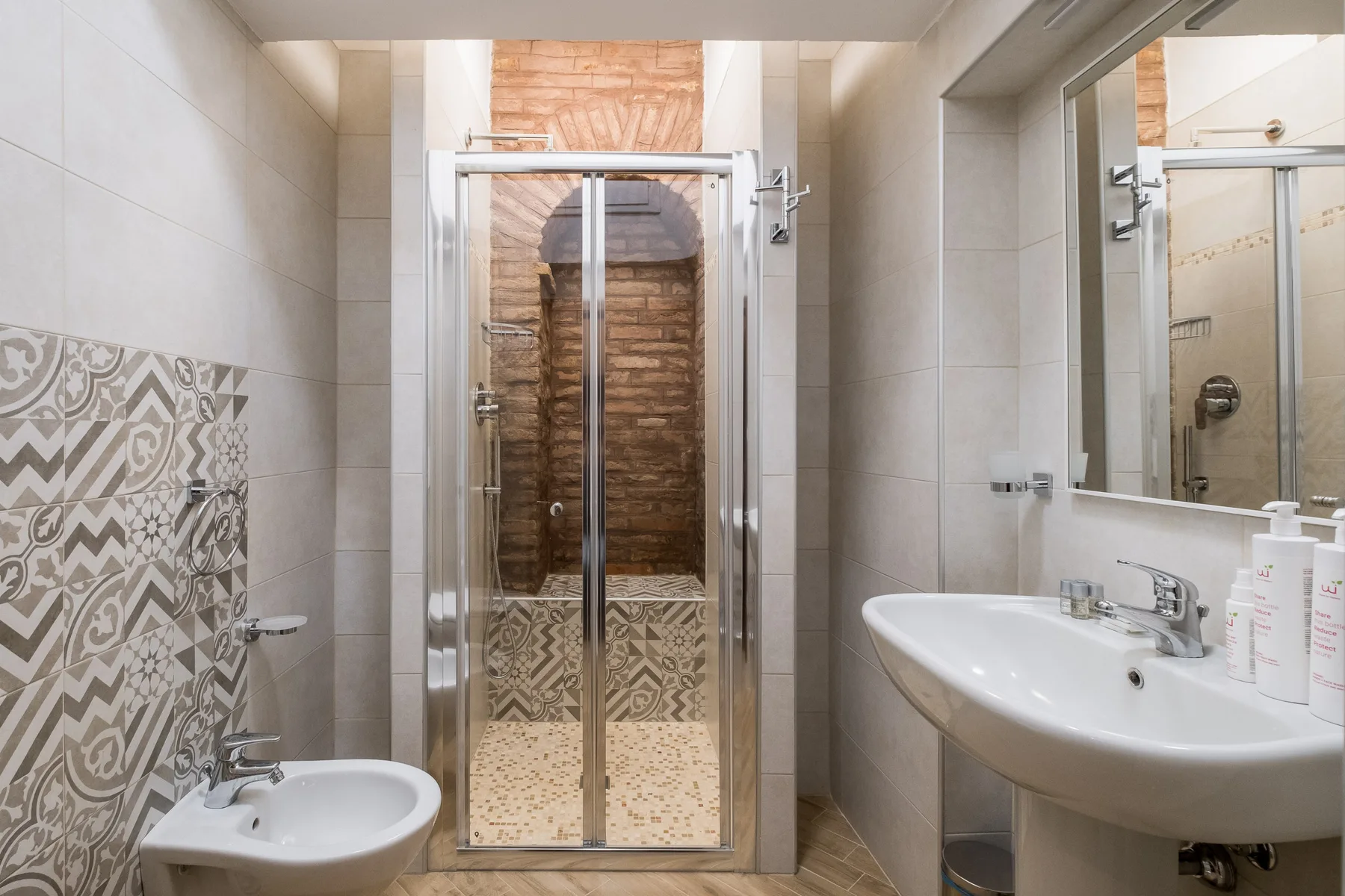 Un baño alicatado con ducha de vidrio, lavabo e inodoro.