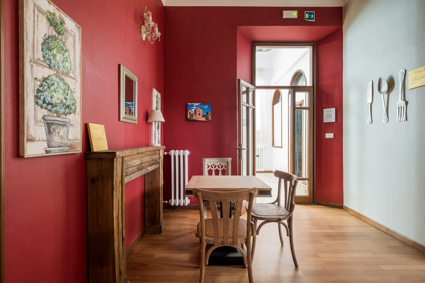 Un comedor con una mesa de madera y sillas junto a una pared roja.