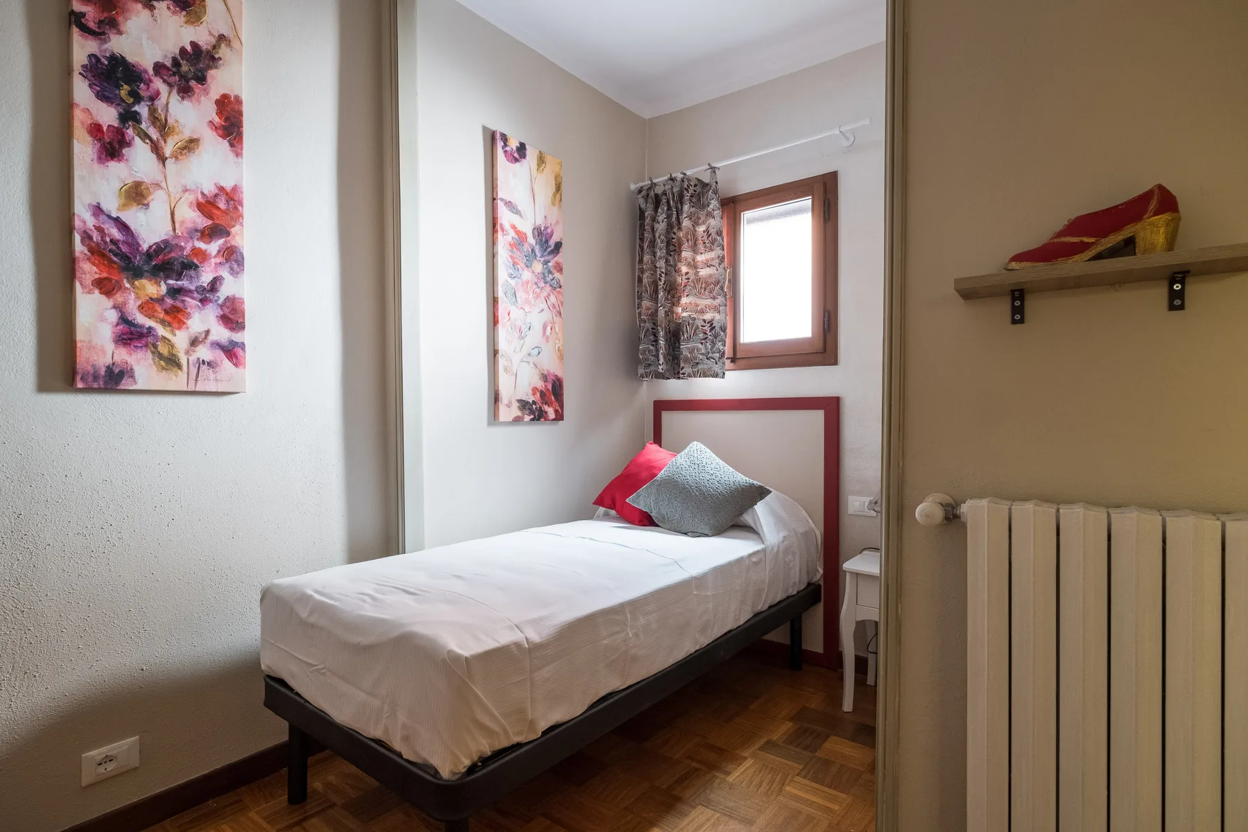 Una cama individual está junto a una ventana en un dormitorio luminoso.