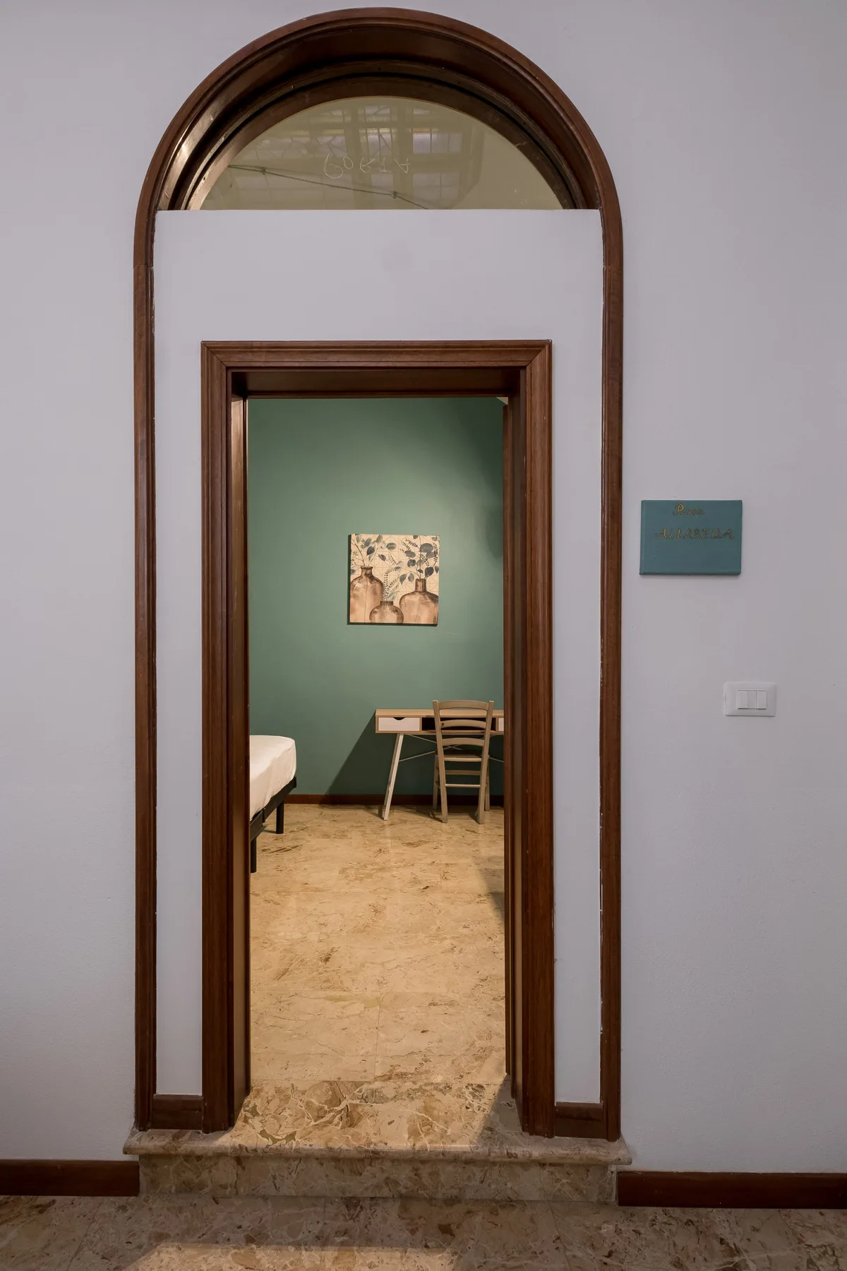 Un arco da paso a una habitación con una pared verde y una mesa pequeña.