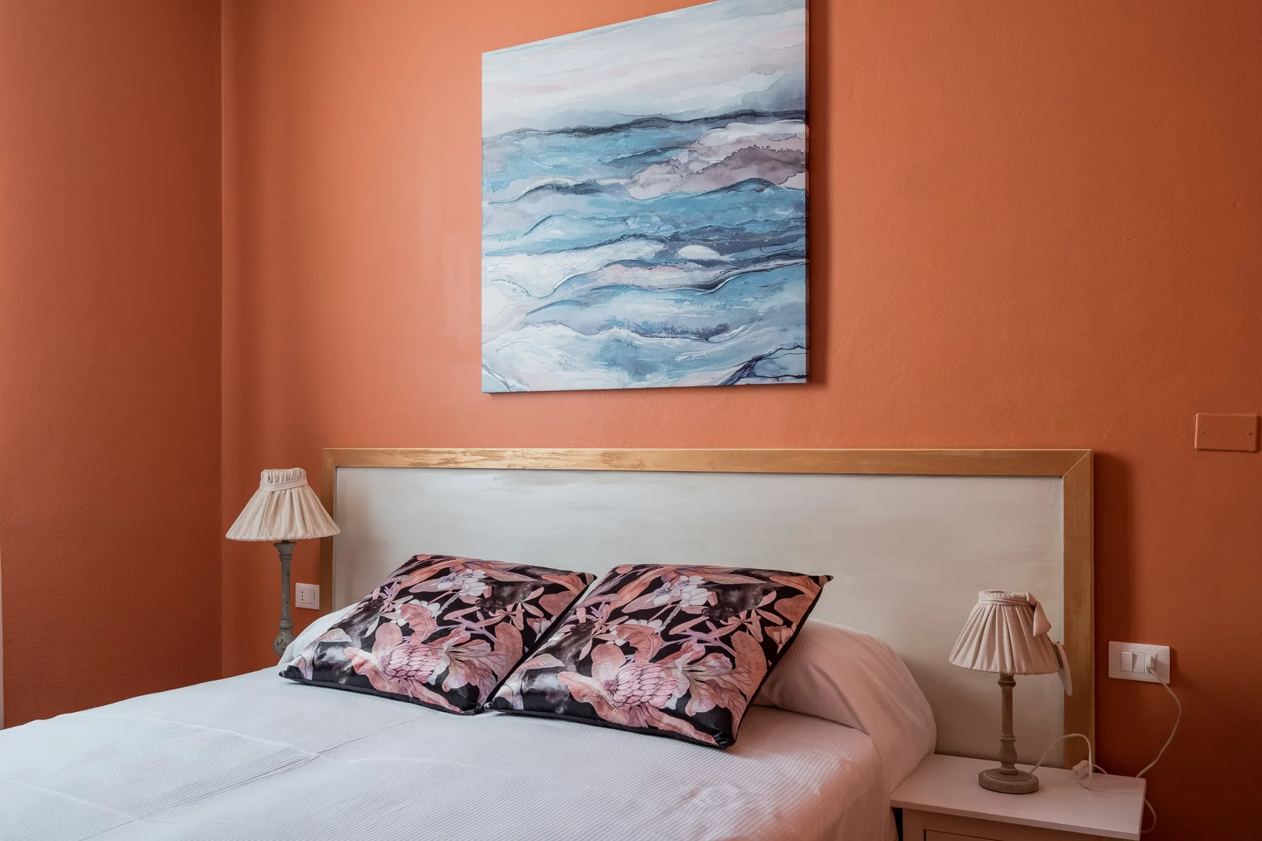 Un dormitorio con una cama bajo una pintura abstracta azul.