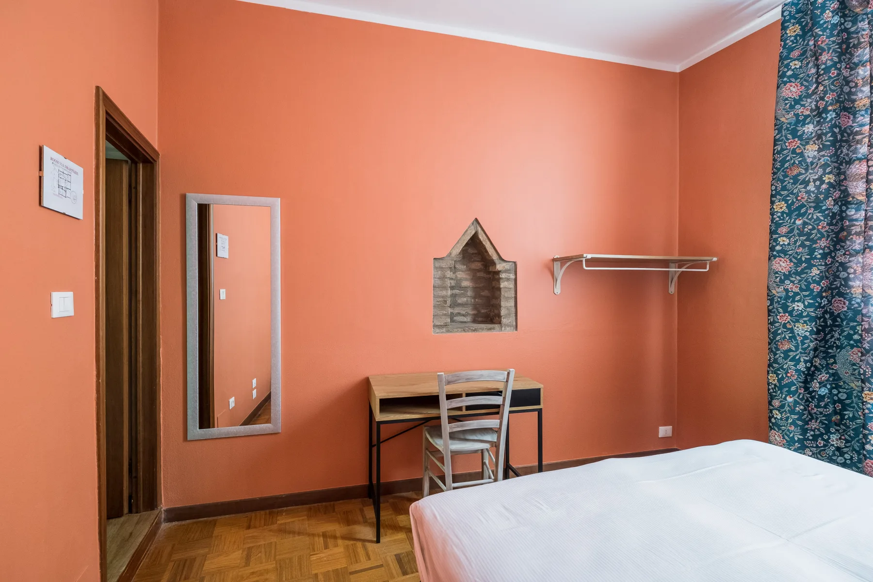Un dormitorio con paredes coral, un escritorio y una silla, y una cama.