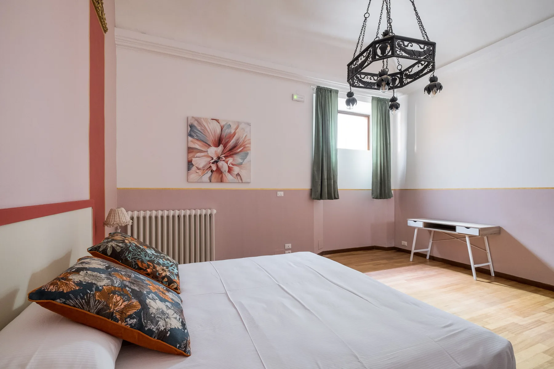 Un dormitorio con una cama, una ventana con cortinas verdes y una mesa pequeña.