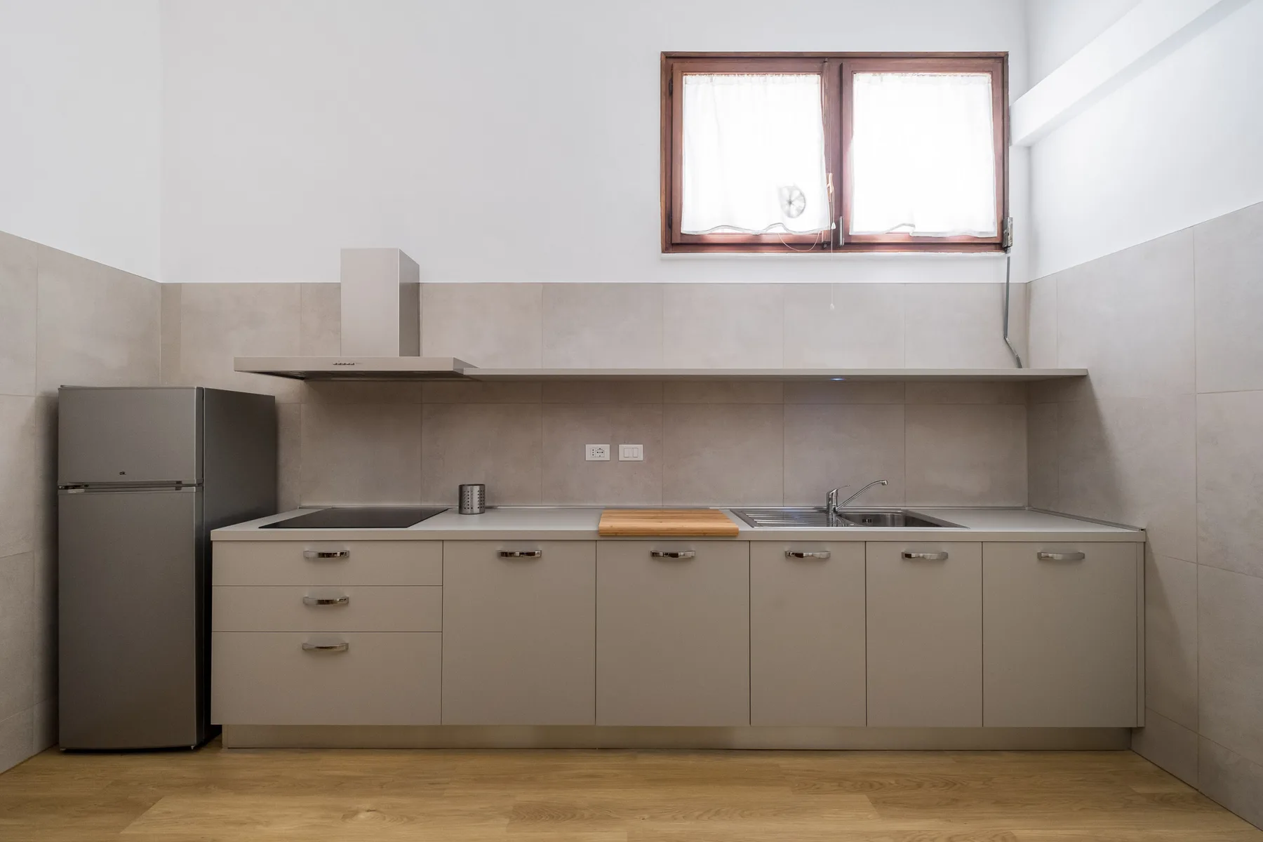 Una cocina luminosa con refrigerador, gabinetes y una encimera larga.