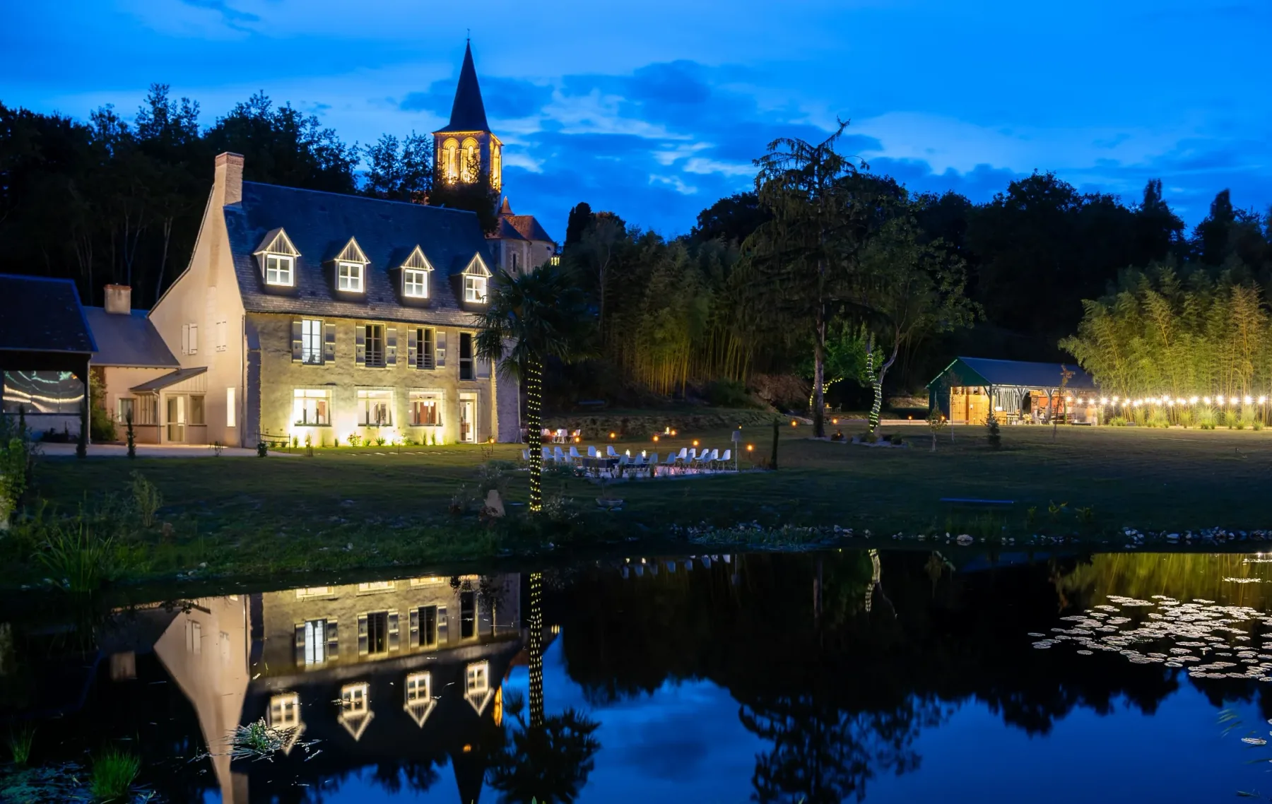 Casa iluminada por la noche, reflejada en el Riverolle