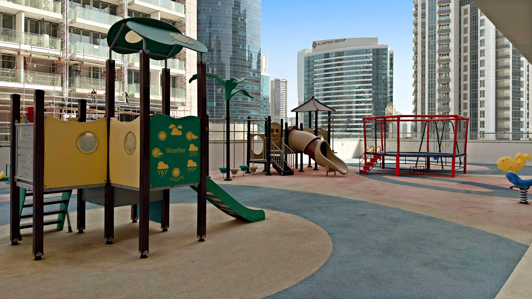 Un parque infantil en la azotea con estructuras para trepar, un tobogán y columpios.