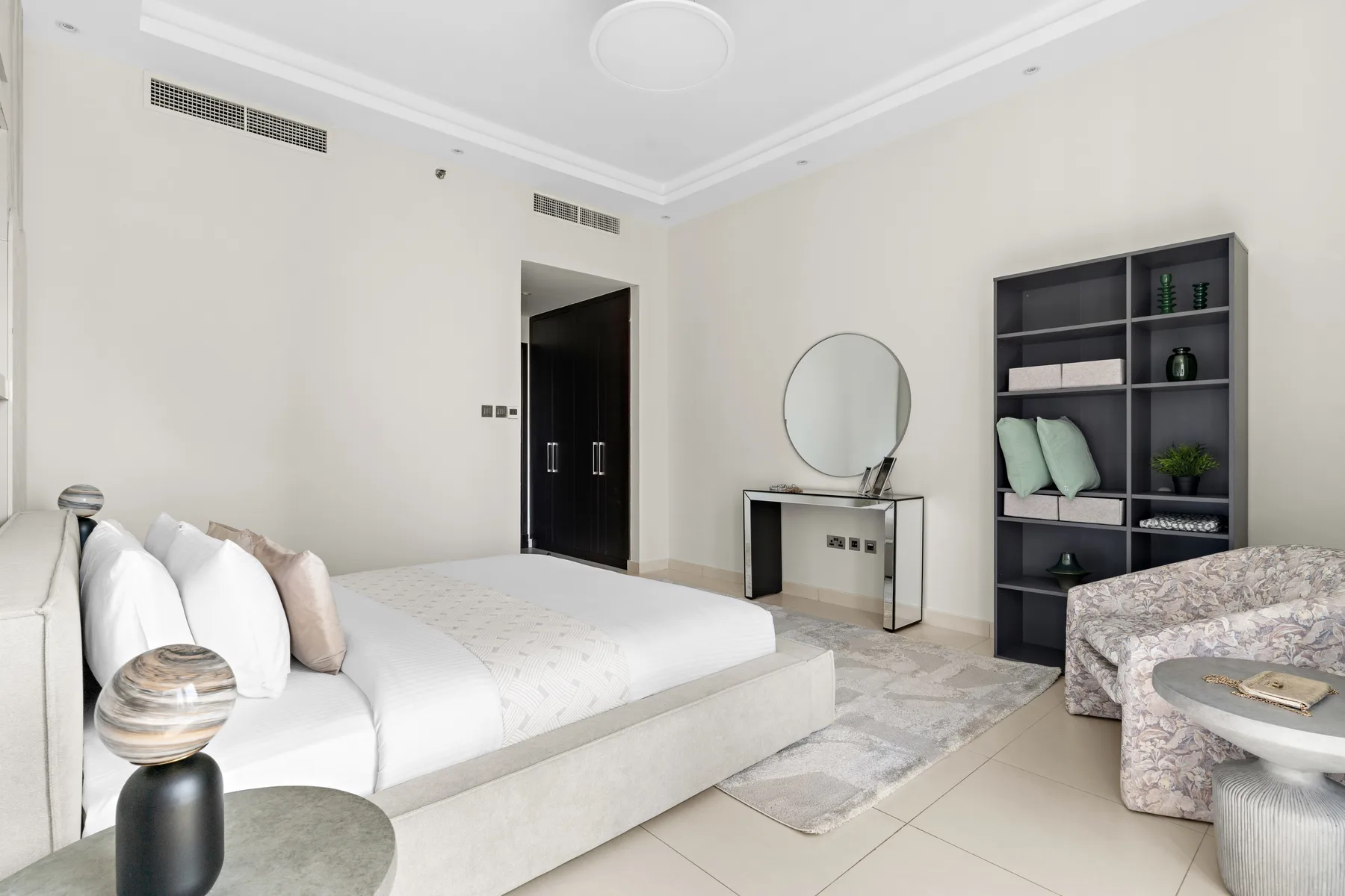 Un dormitorio luminoso con una cama baja, un tocador y estanterías abiertas.