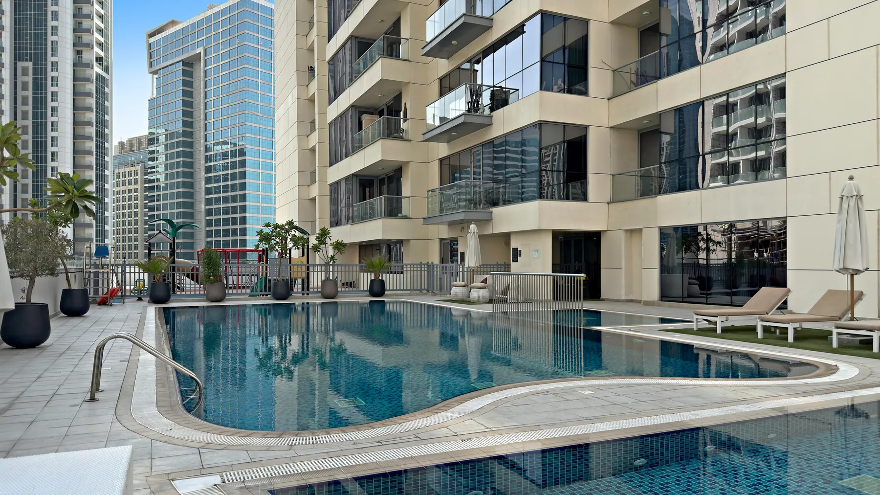Una piscina al aire libre junto a modernos edificios de gran altura.