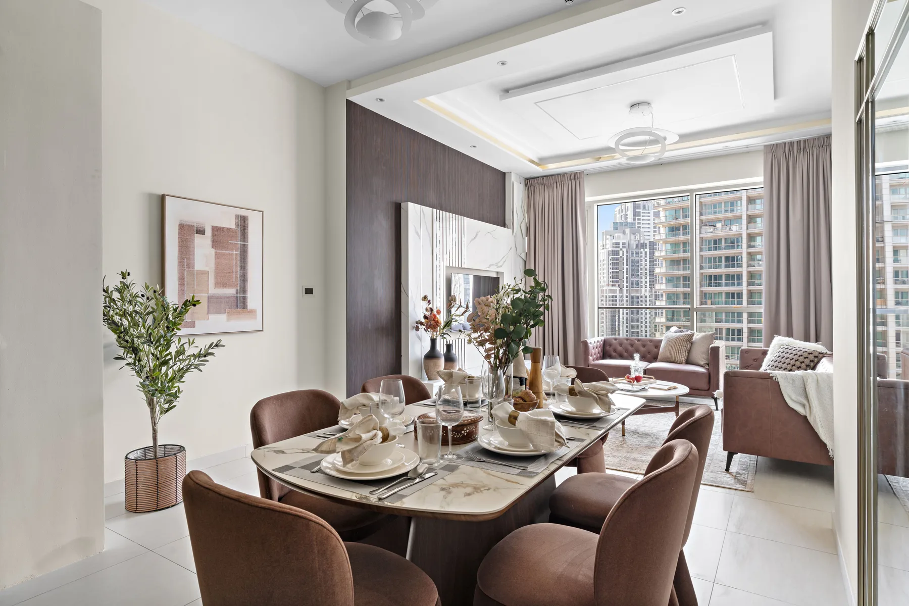 A dining area with a set table beside a bright living room and large windows.