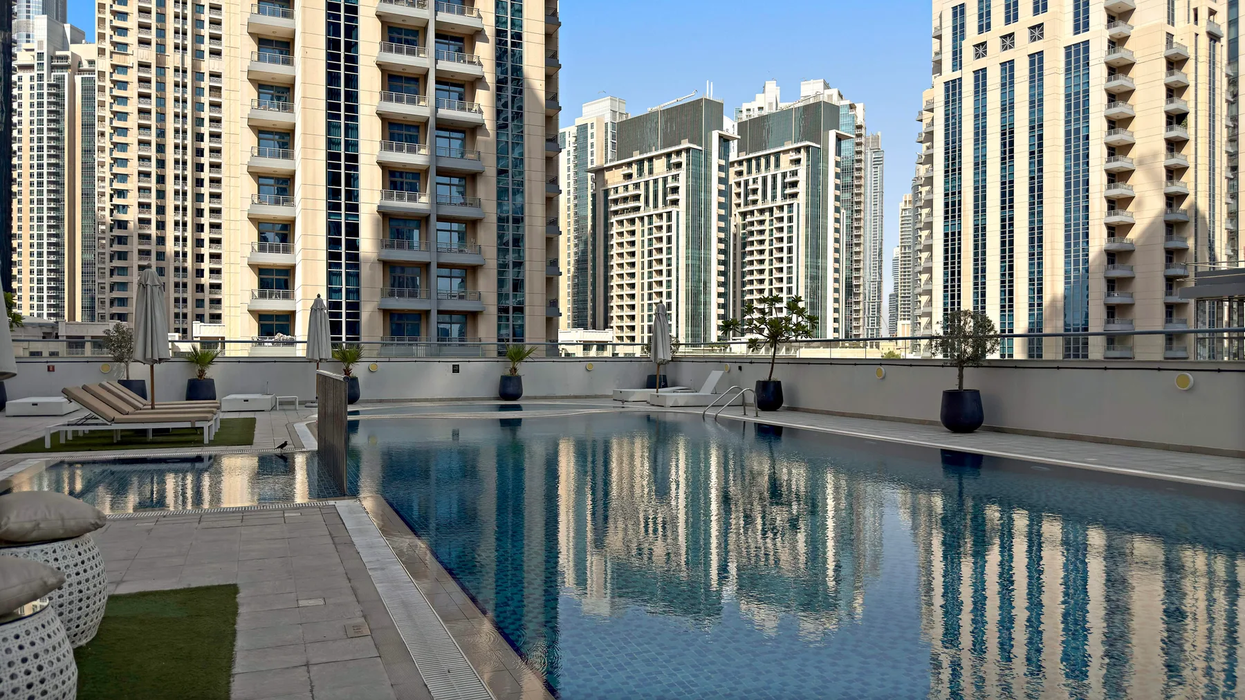 Una piscina al aire libre refleja los edificios altos que la rodean.