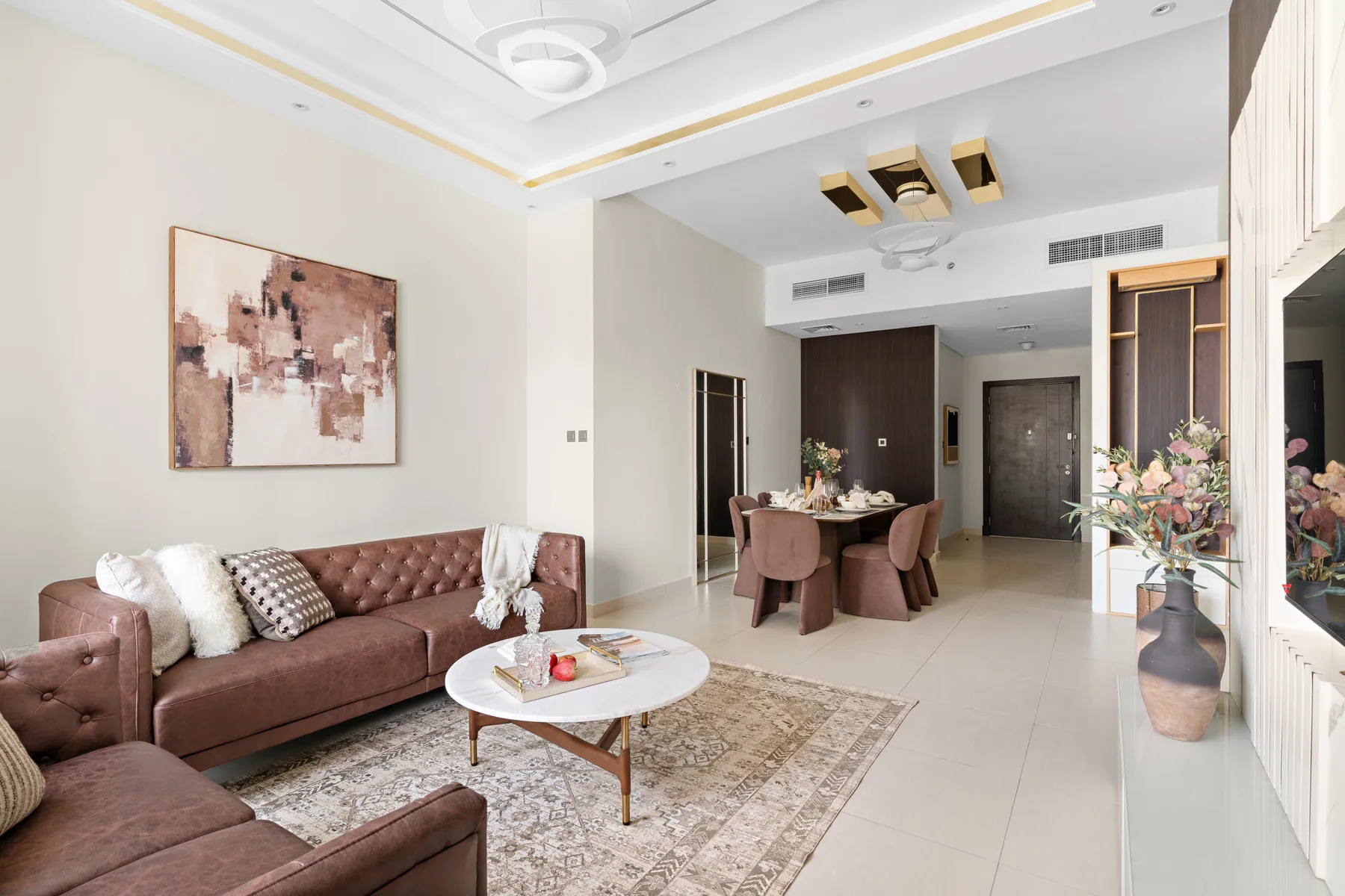 A living and dining room with seating, a dining table, and wall art.