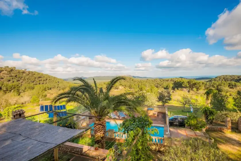 A hillside landscape overlooks a swimming pool and surrounding greenery.