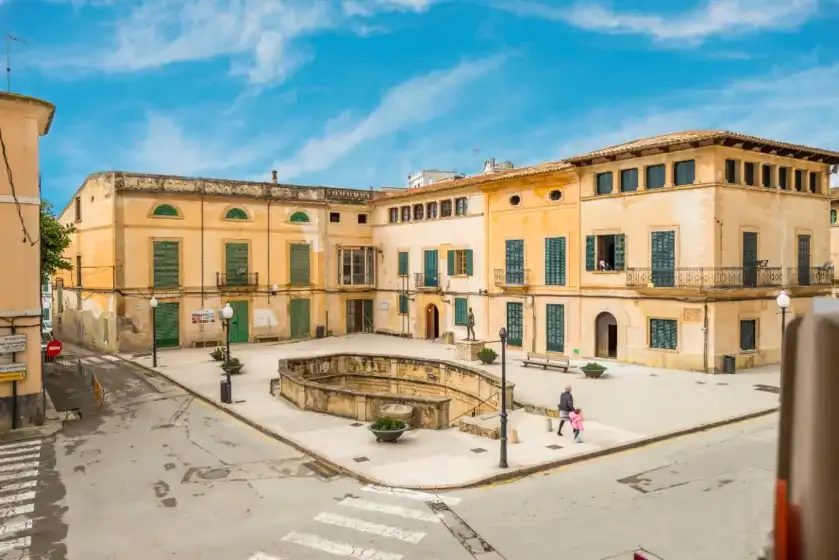 Una plaza pavimentada se extiende frente a una hilera de edificios amarillos claros.