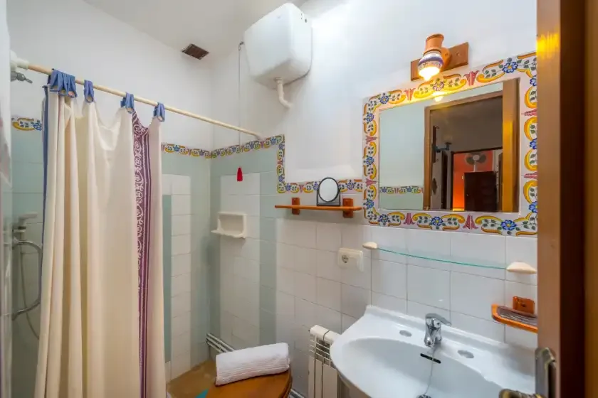 Un baño alicatado con lavabo y una ducha con cortina.