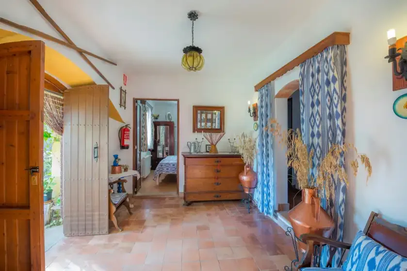 Un pasillo interior luminoso con una cómoda de madera y cortinas estampadas.
