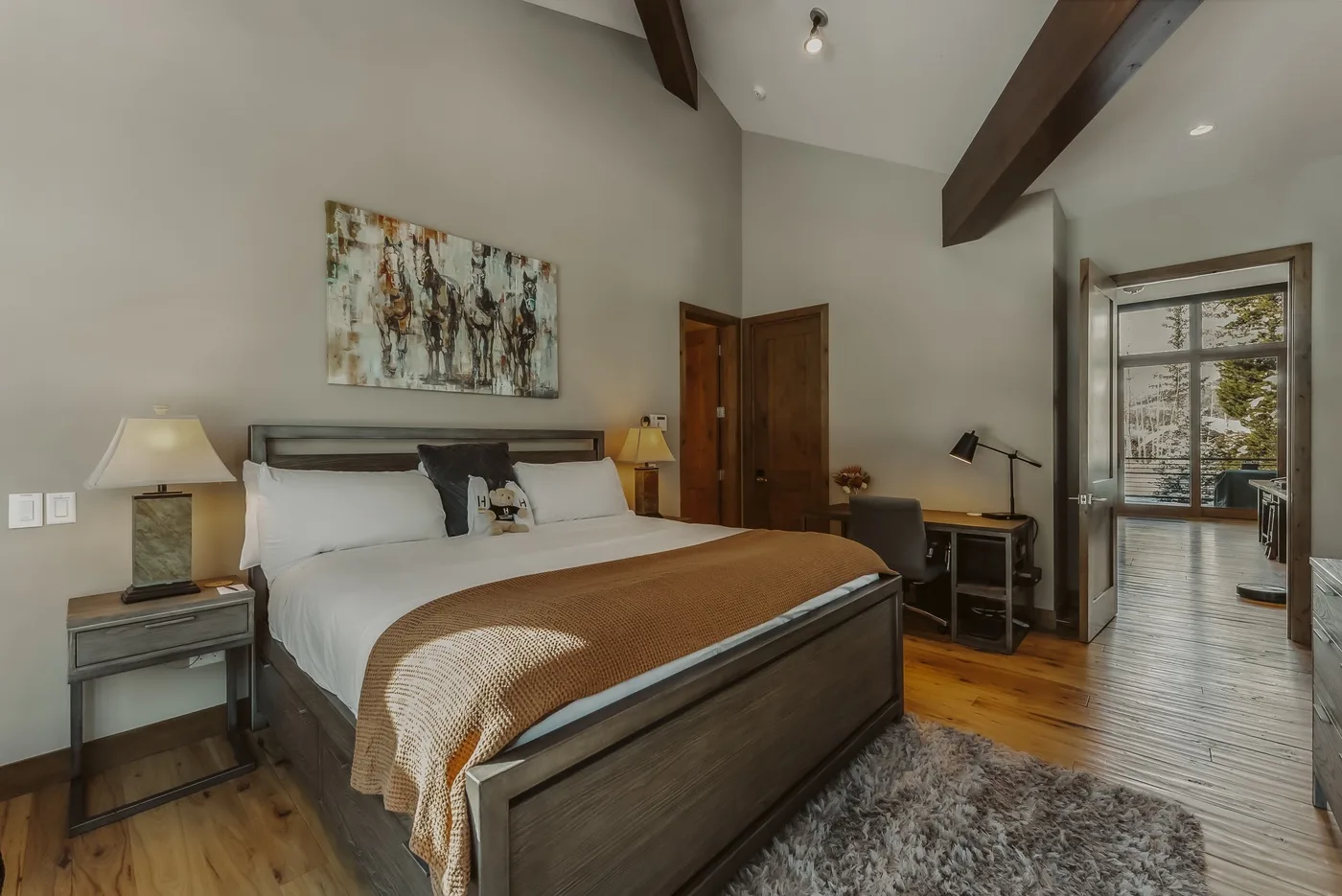 A bedroom with a large bed, bedside tables, and exposed ceiling beams.