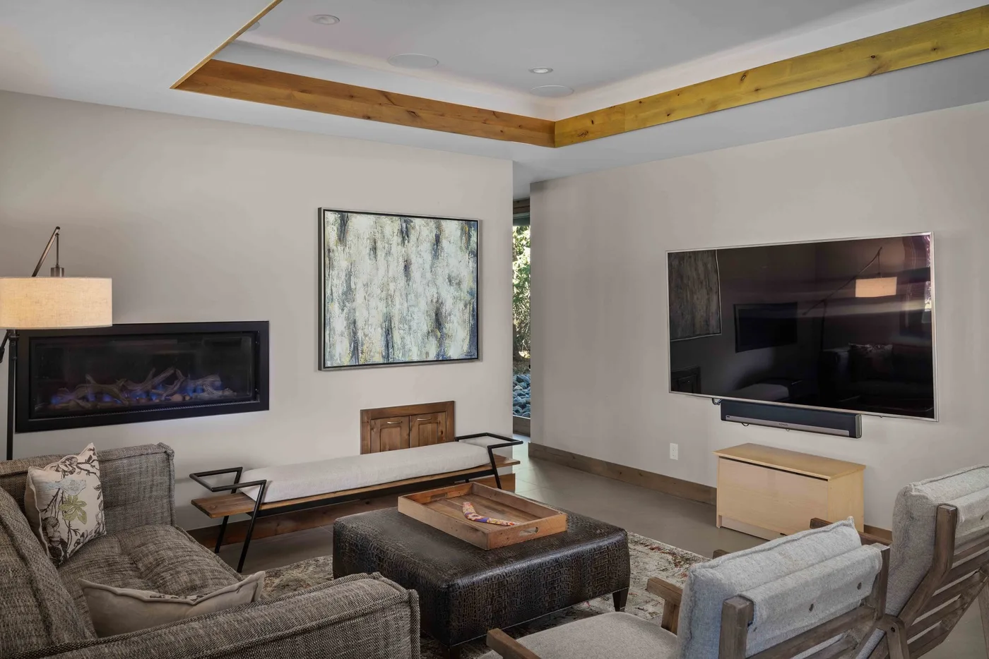 A living room with seating arranged around a coffee table and a wall-mounted television.